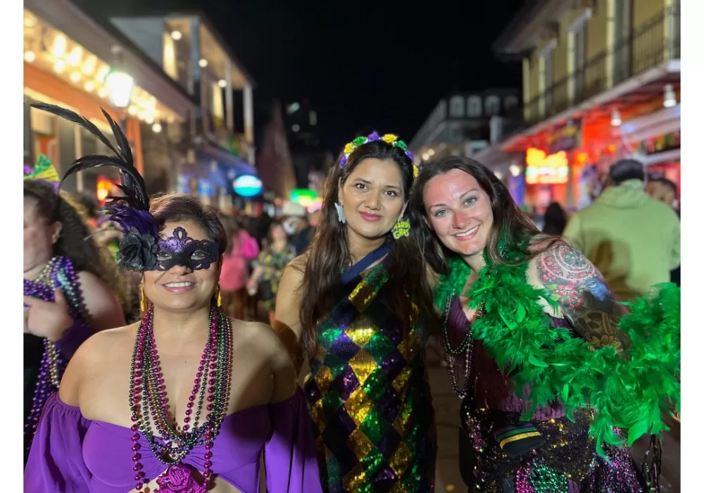 3 women in Mardi Gras outfits on Bourbon Street