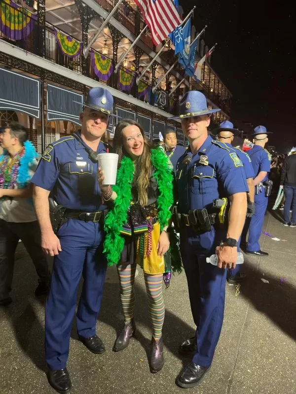 Woman holding drink standing in between two police officers at Mardi Gras New Orleans 