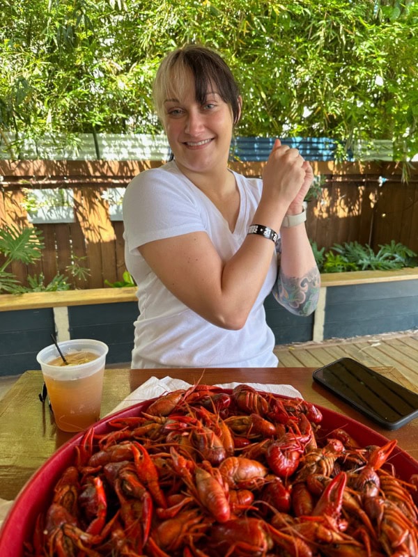 Woman dancing in front of a large plate of boiled crawfish.