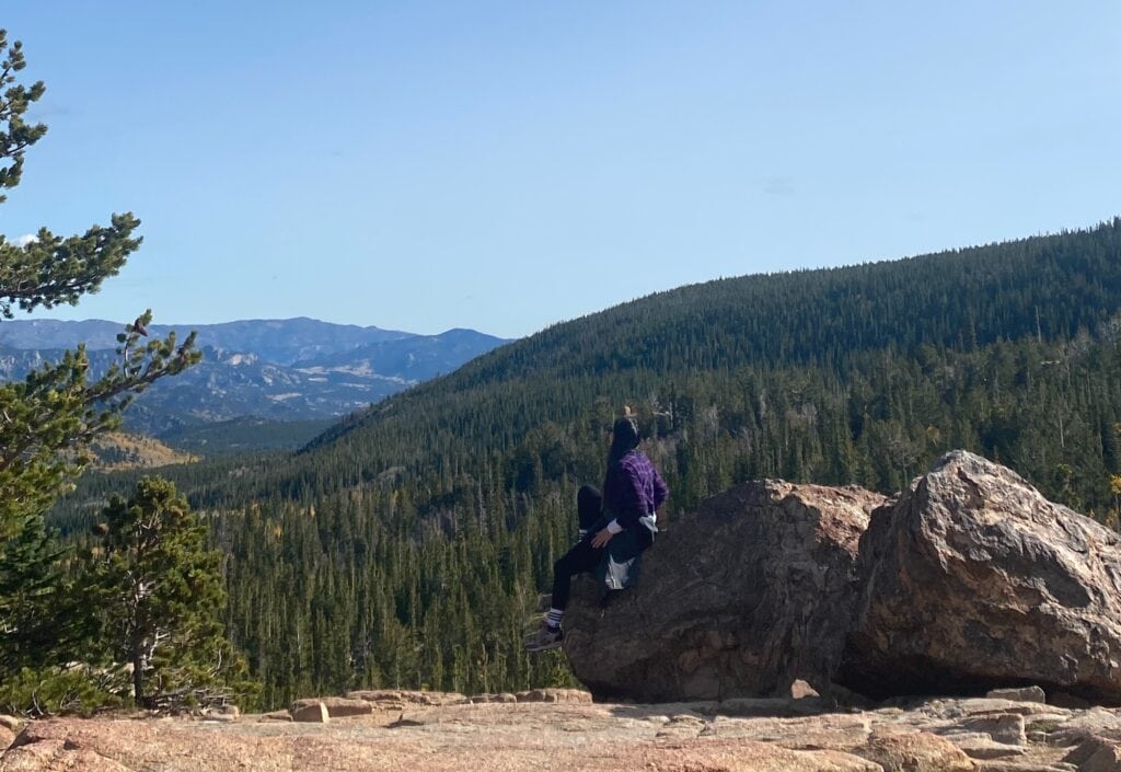 Woman sitting on rock overlooking mountains