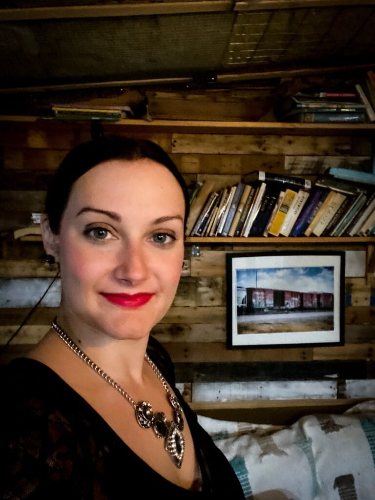 Woman wearing black dress posing in front of books on a shelf