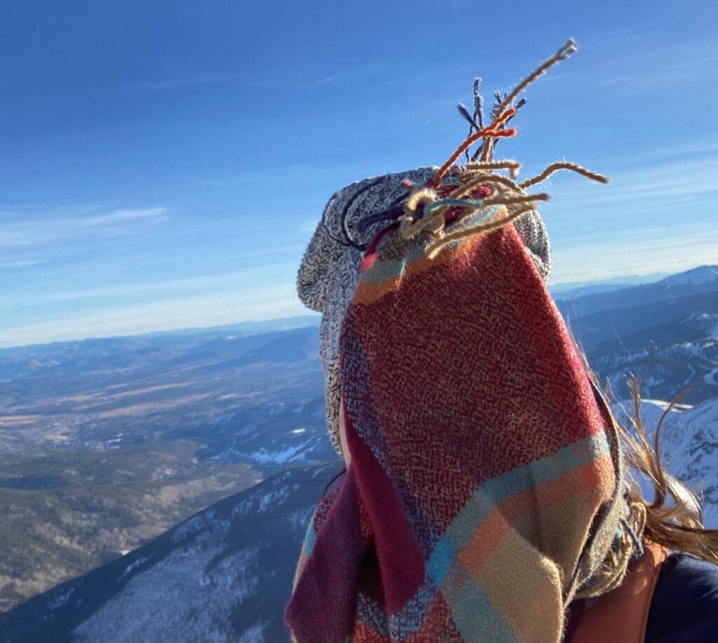 woman on top of windy mountain with scarf blowing in face