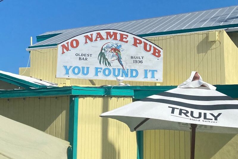 exterior of No Name Pub. Yellow buildin g with "you found it" sign