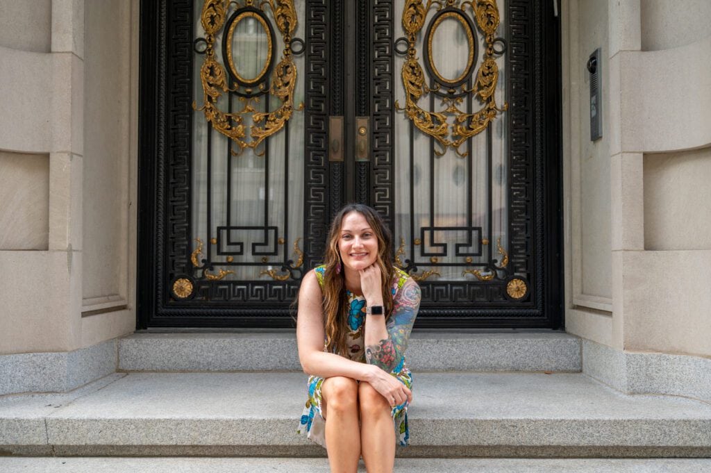 Woman sitting on steps in front of elaborate door