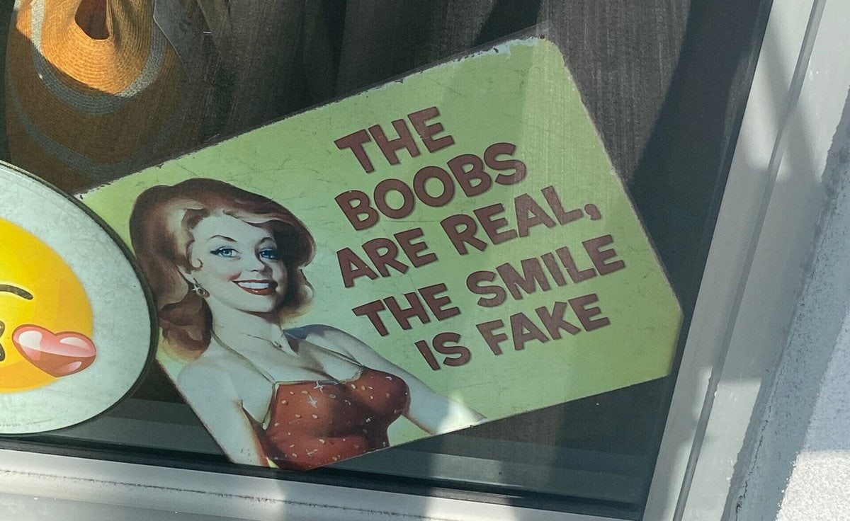 sign that reads "the boobs are real. the smile is fake."
