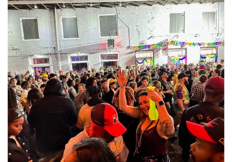 woman smiling and holding yellow drink in the middle of a huge crowd at Mardi Gras