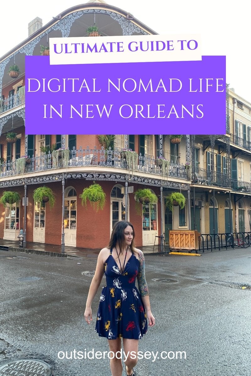 A woman in a navy floral dress stands on a wet street before a historic New Orleans building. Text reads, Ultimate Guide to Digital Nomad New Orleans Life.