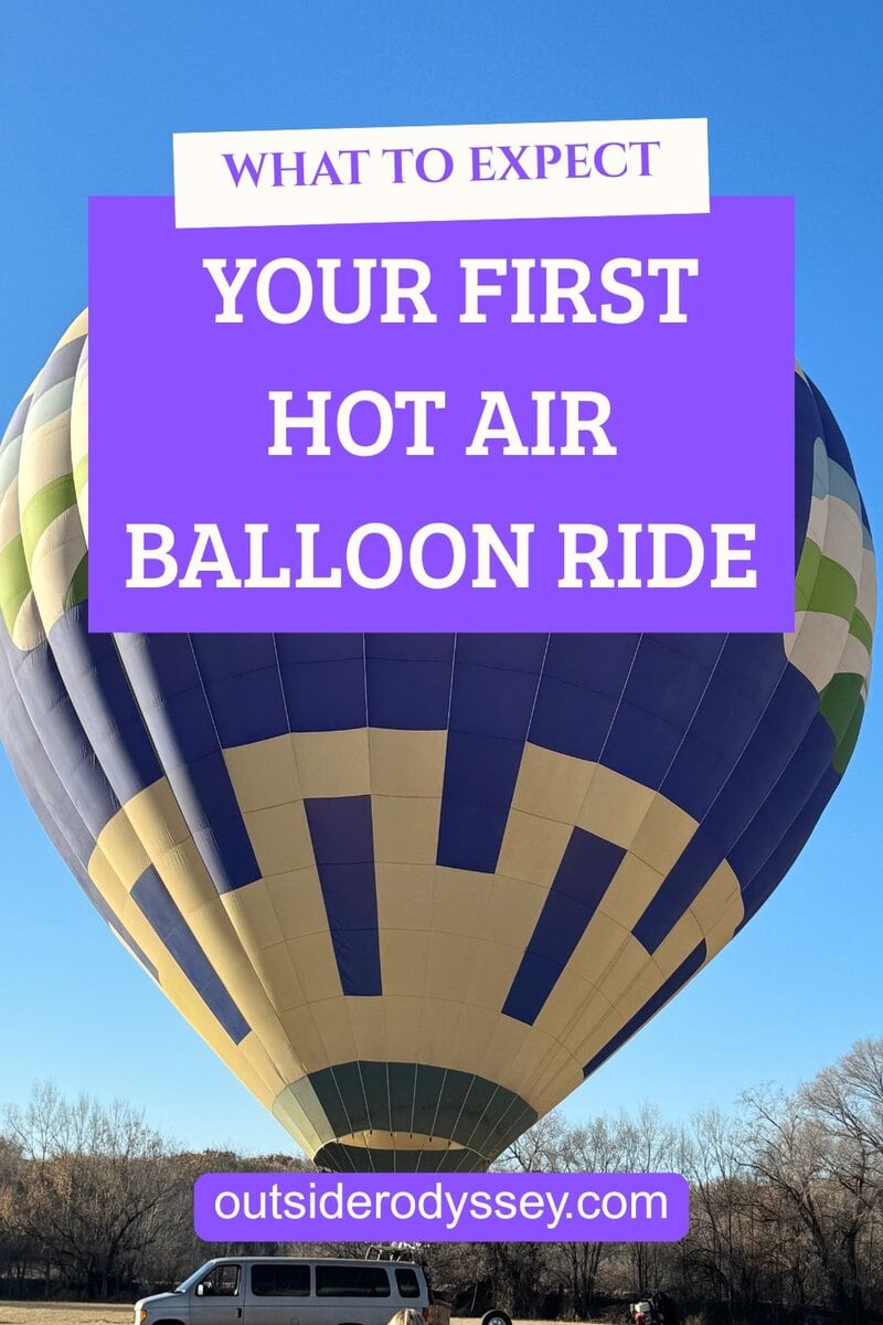 A large hot air balloon with blue, green, and beige patterns is being inflated on a sunny day. A white van is parked nearby. Overlays read “What to expect: Riding in a hot air balloon” and “outsiderodyssey.com.”.