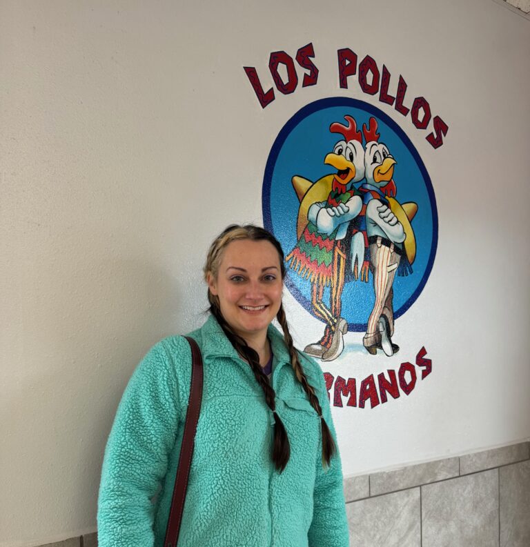 A woman standing in front of a sign.