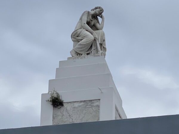 A large tombstone with a statue of a woman resting with her face in her hand. At St. Lous Cemetery No. 1 in New Orleans