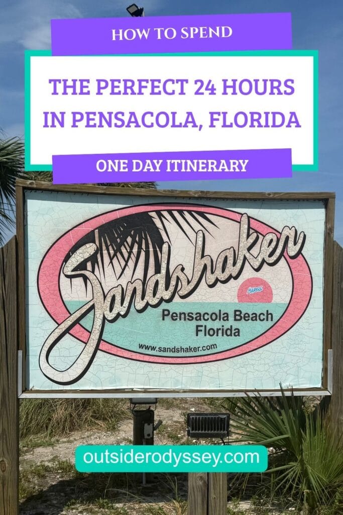 A sign for Sandshaker in Pensacola Beach, Florida, with text above promoting a one-day itinerary for spending 24 hours in Pensacola. The website outsiderodyssey.com is listed at the bottom, inviting visitors to explore how to make the most of 24 hours in Pensacola.